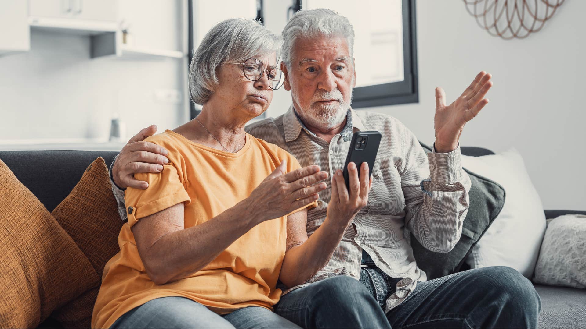 Older couple looking annoyed staring at their phone.