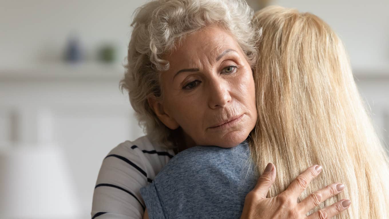 Older woman looking sad while hugging her adult daughter