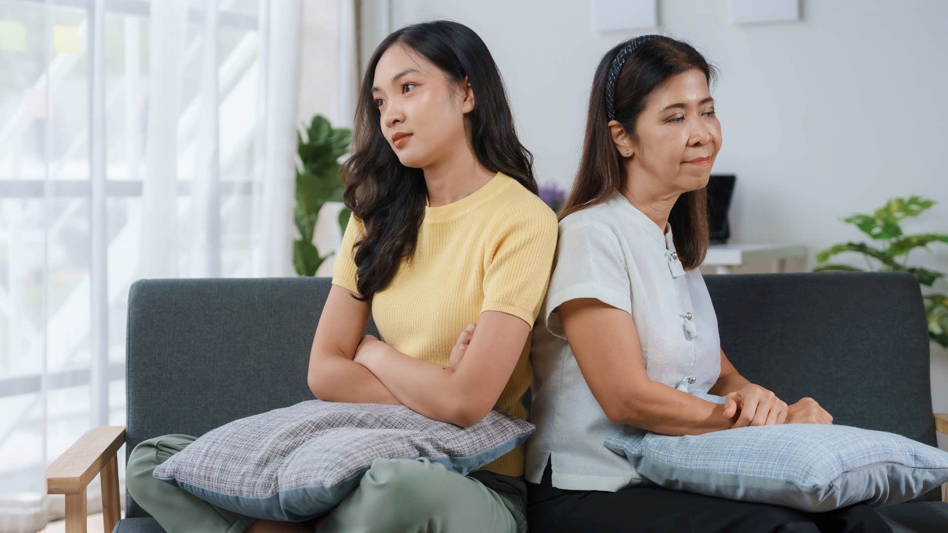 Woman turned away from her upset mother on the couch.