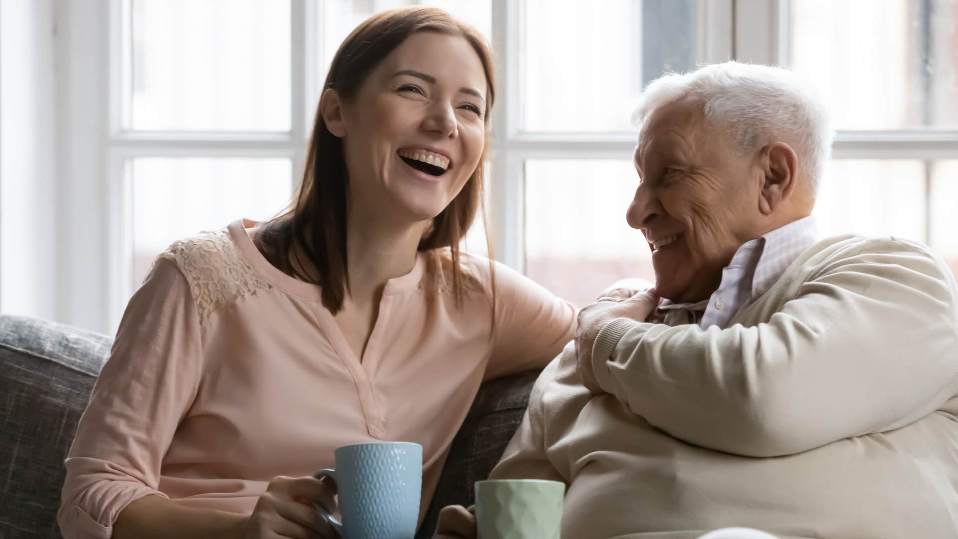 Woman smiling and laughing next to her older dad.