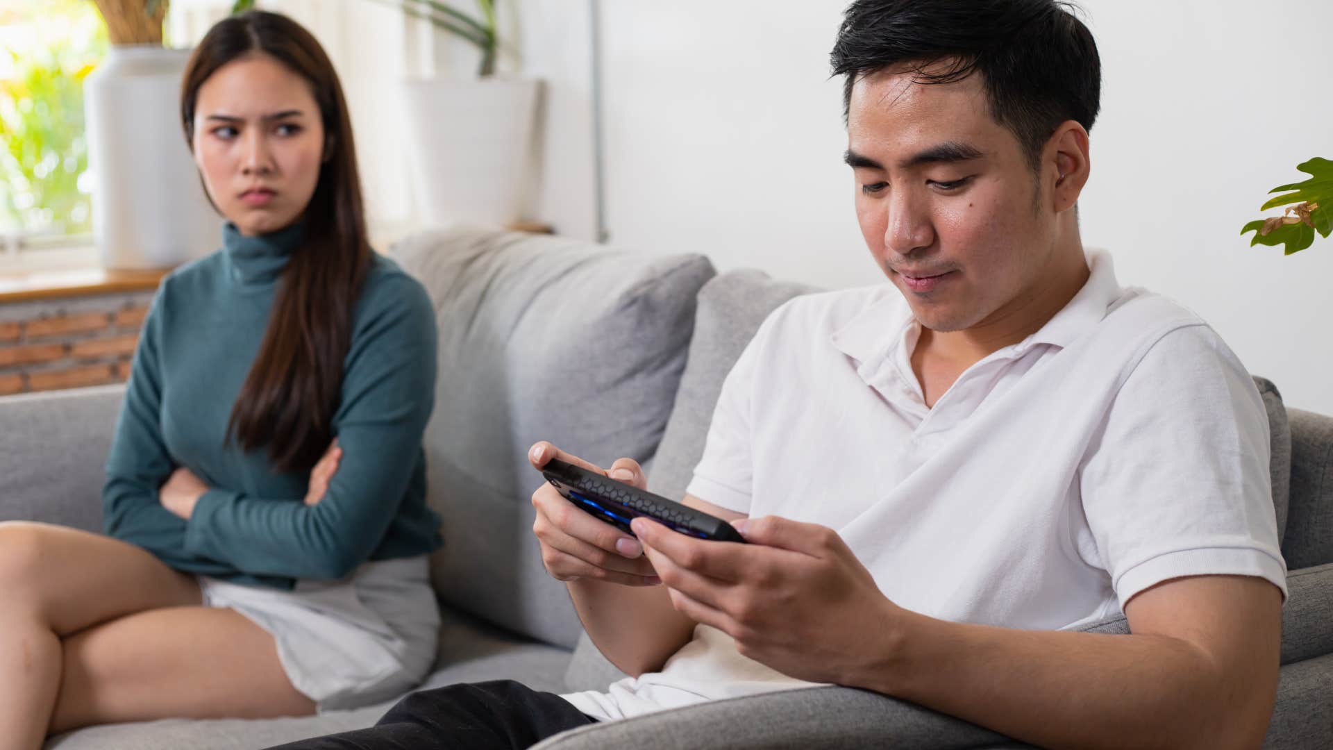 Distracted man texting in front of his upset wife