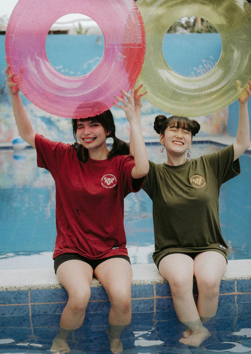 teen girls sitting by pool holding innertubes 