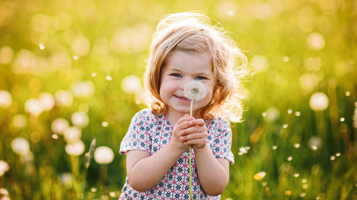 happy little girl holding a dandelion