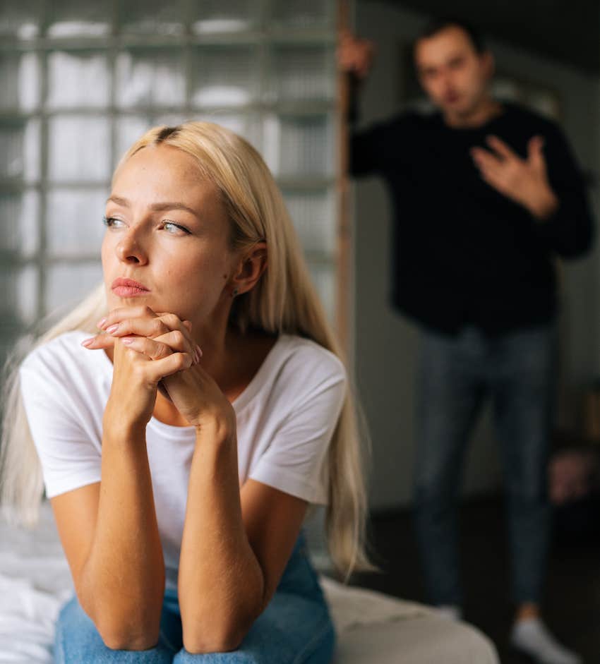 Angry man gestures behind upset woman, trapped in subserviant marriage