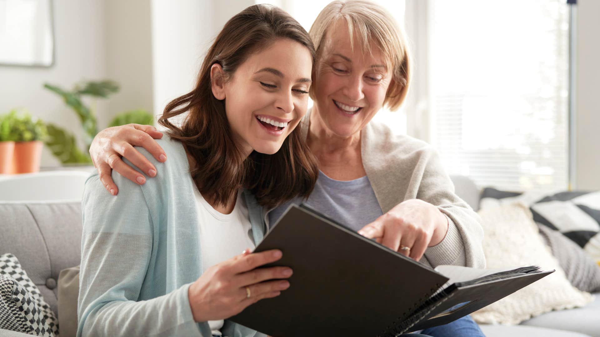 boomer woman looking at photo album with her daughter