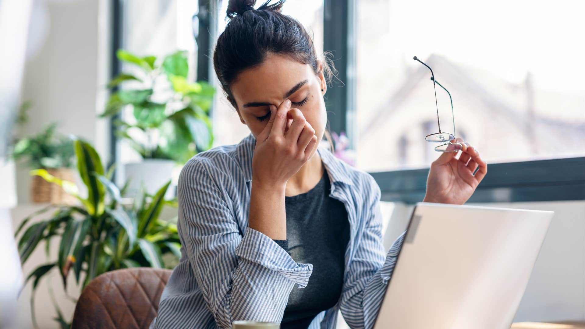 Tired woman holding her head in her hands at work.