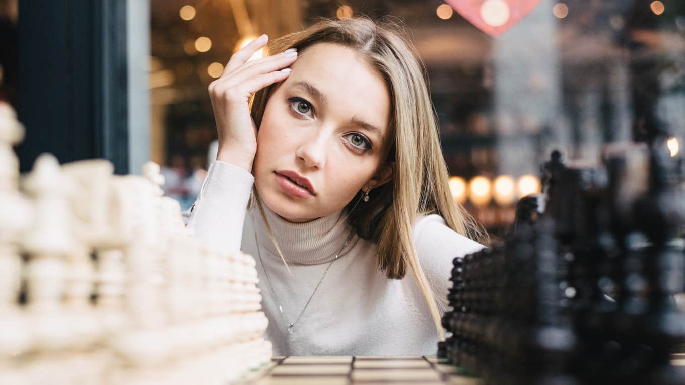 Beautiful girl play chess, queen gambit play and everyone wins, a smart and pensive face.