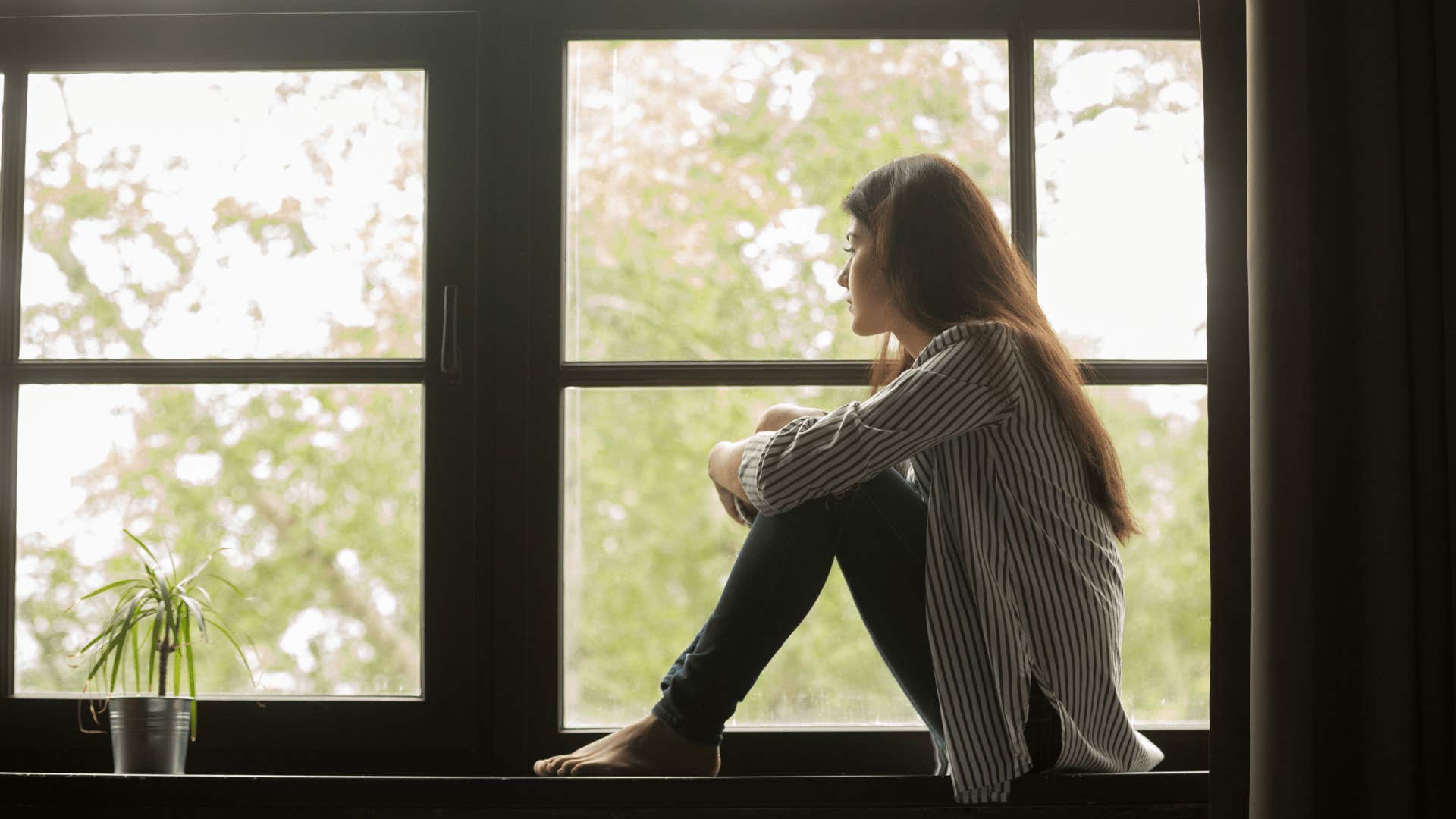 alone woman sitting on window sill