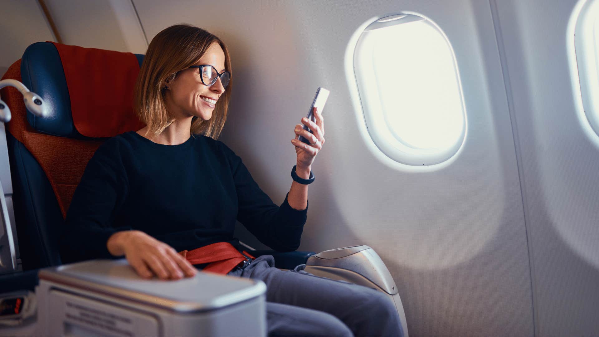 woman looking at her phone on an airplane