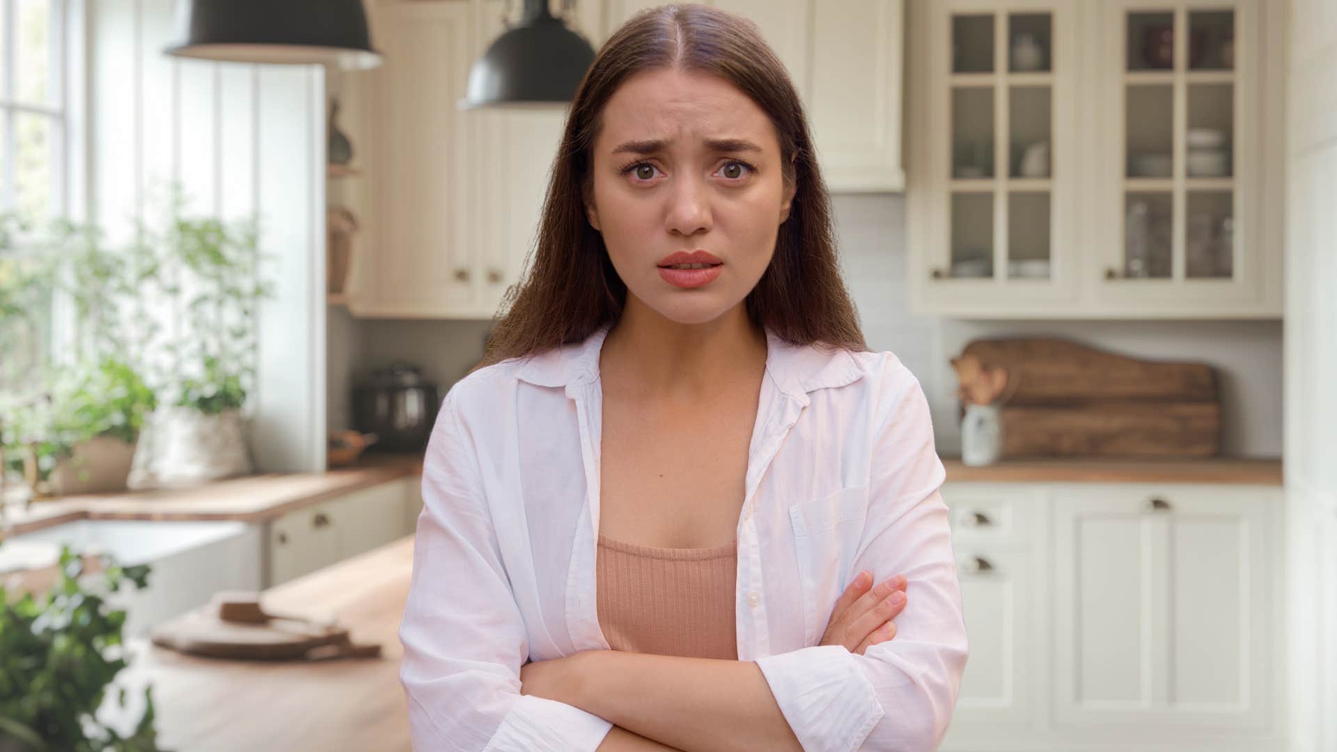 Gen Z woman looking shocked in a farmhouse chic-styled kitchen.