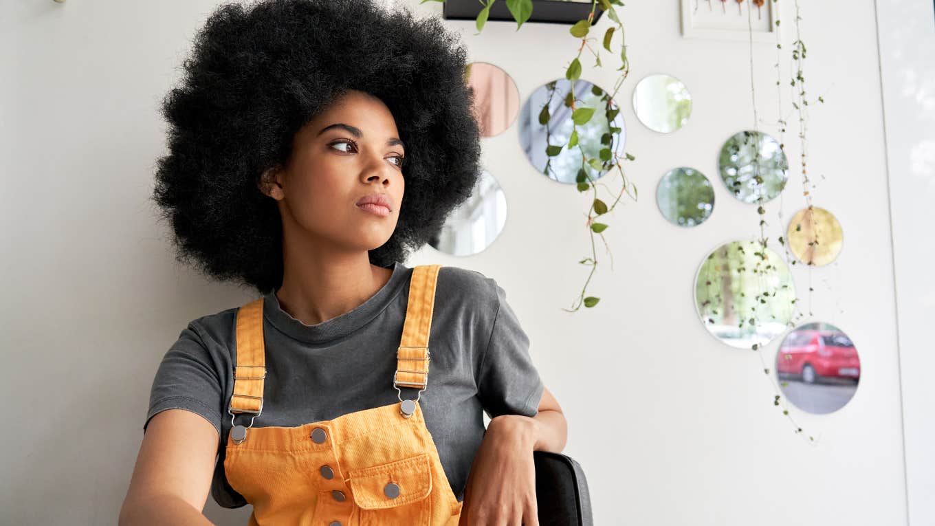 Gen Z woman looking upset sitting in her home.