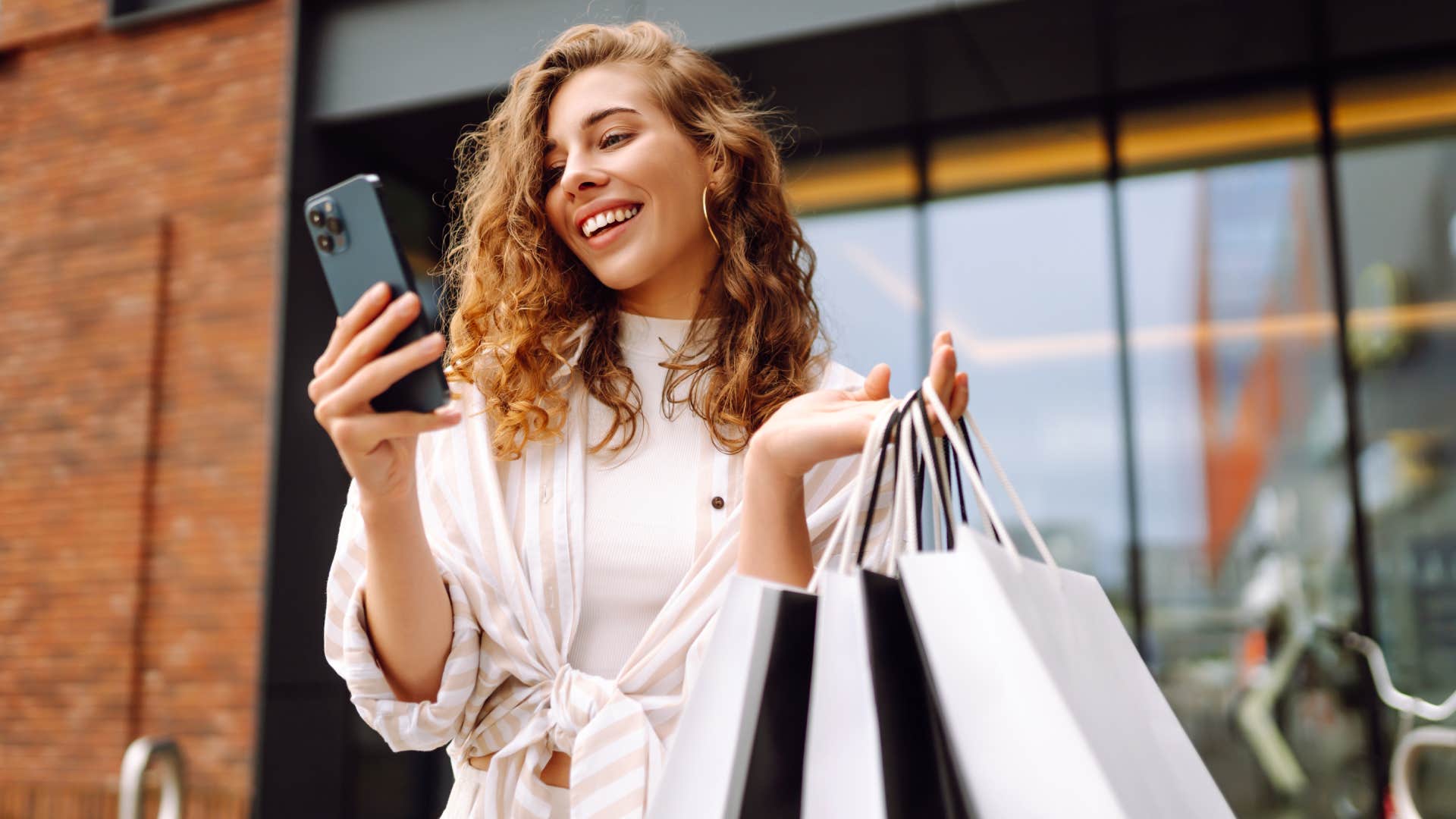 Young Woman use of mobile phone and hold with shopping bag.