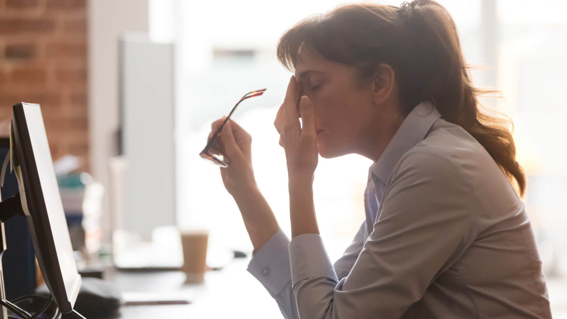 gen z woman rubbing her temples at work