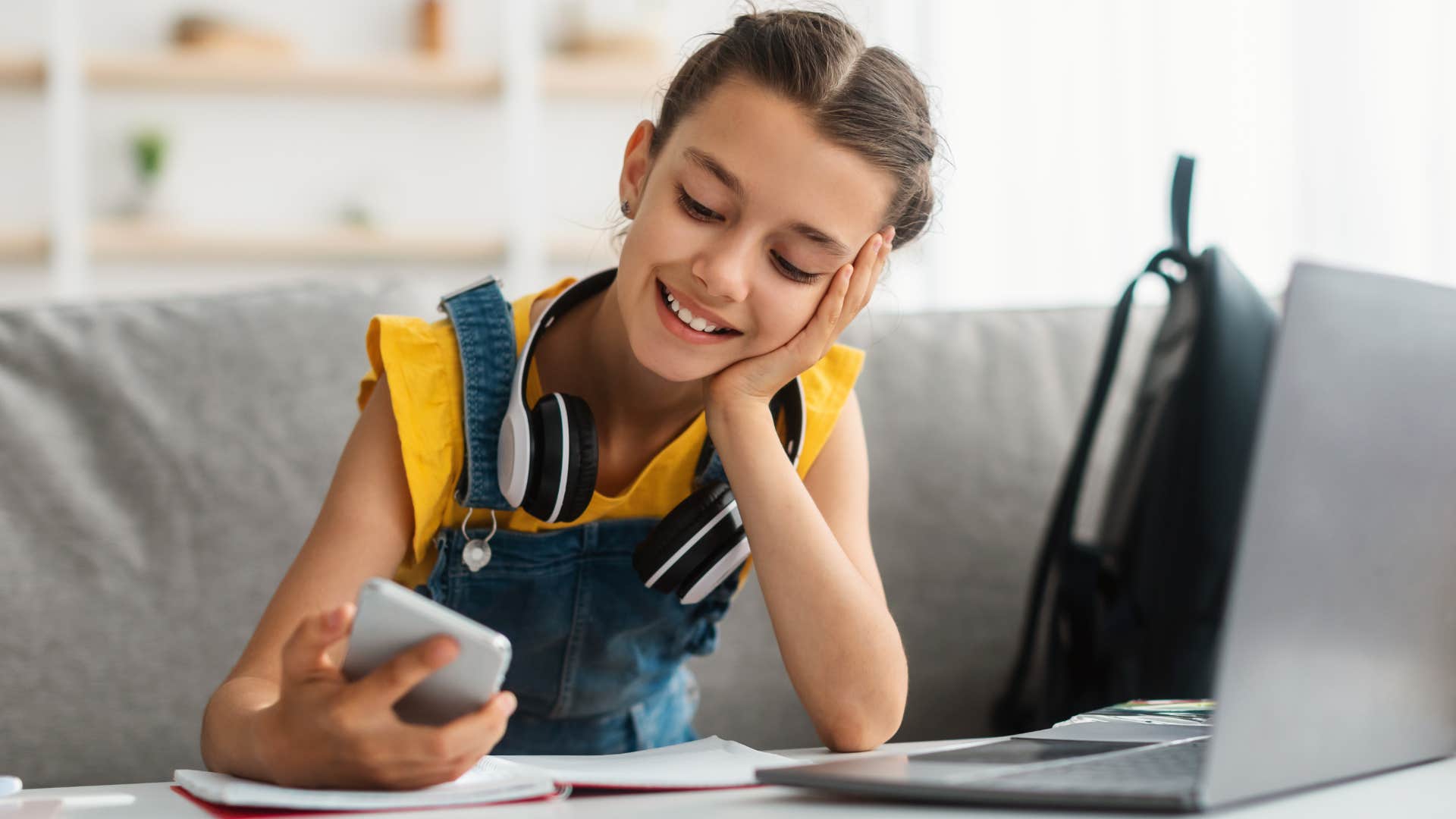 Young girl smiling and scrolling on her phone.