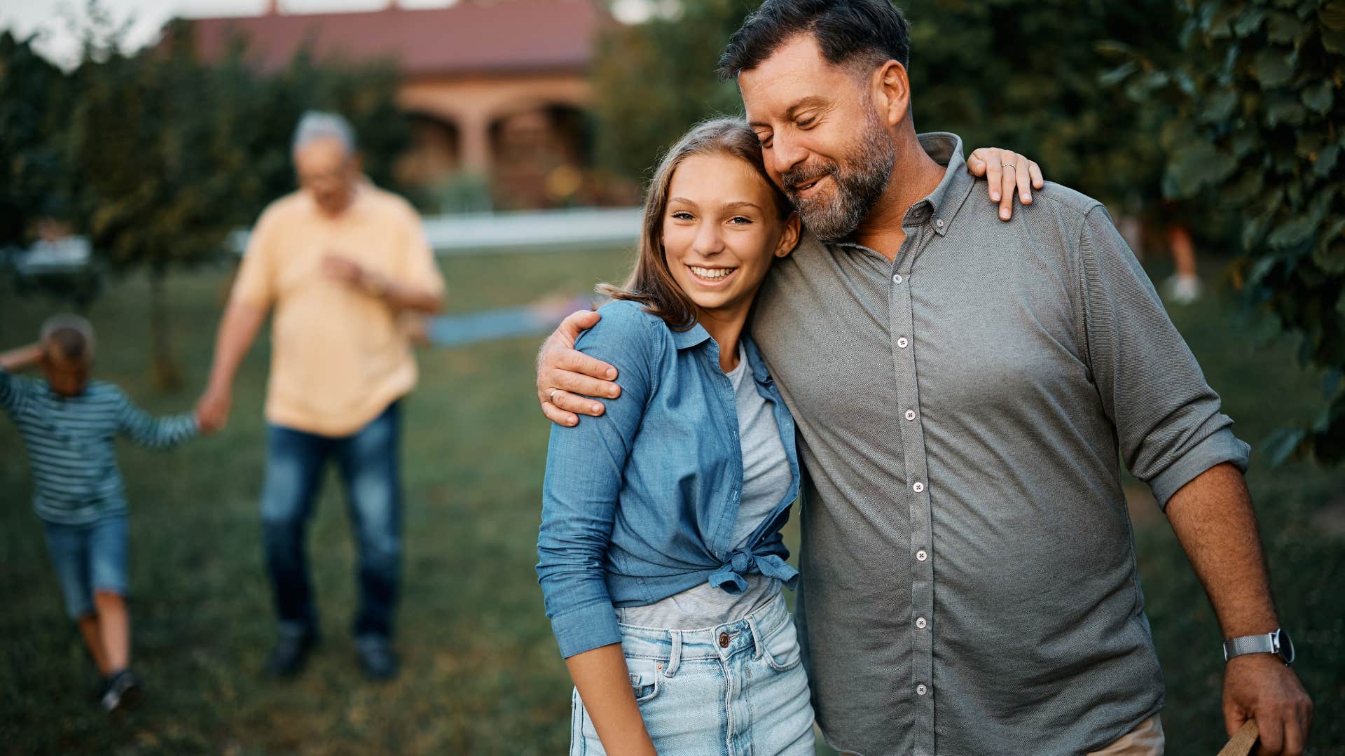 Dad hugging his teenage daughter outside.