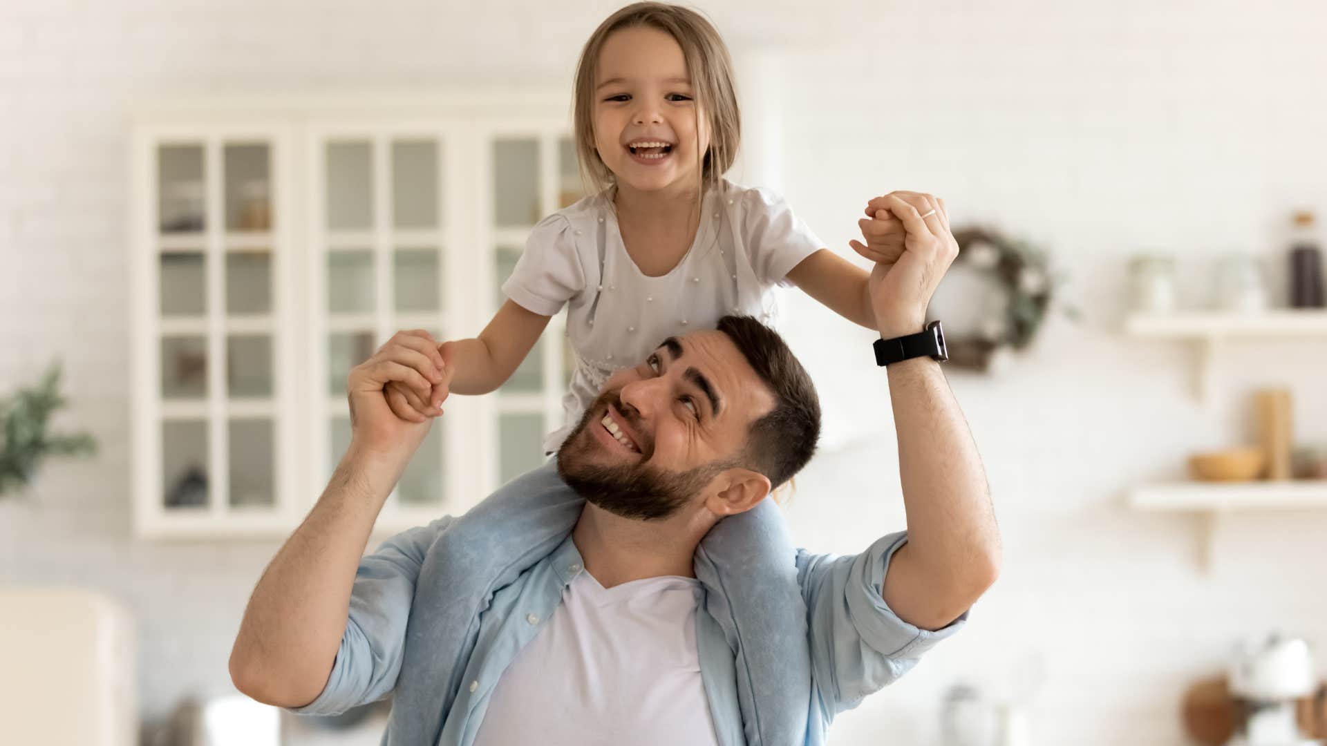 Father holding up his smiling daughter on his shoulders.