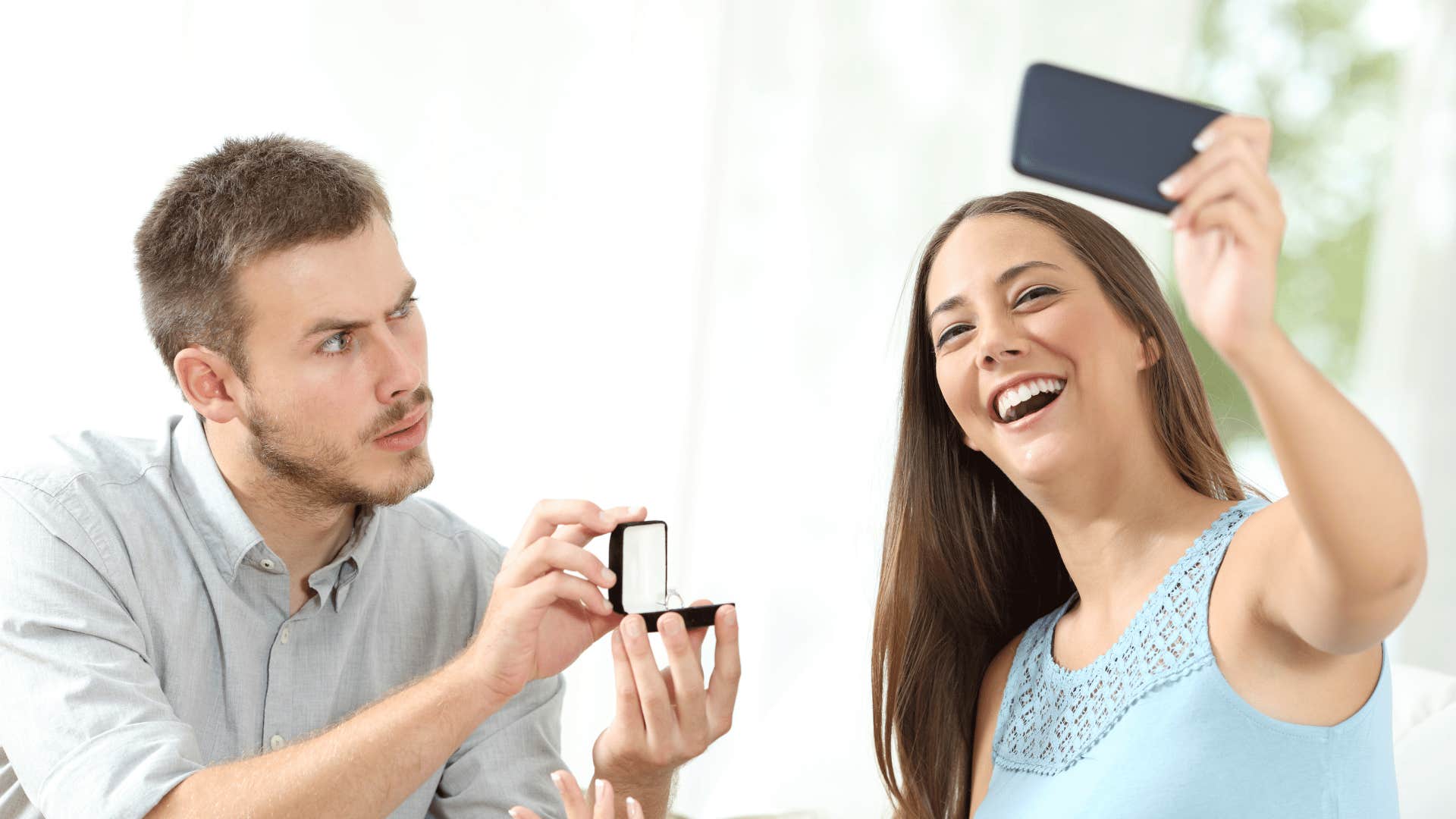 woman taking a selfie while man proposing