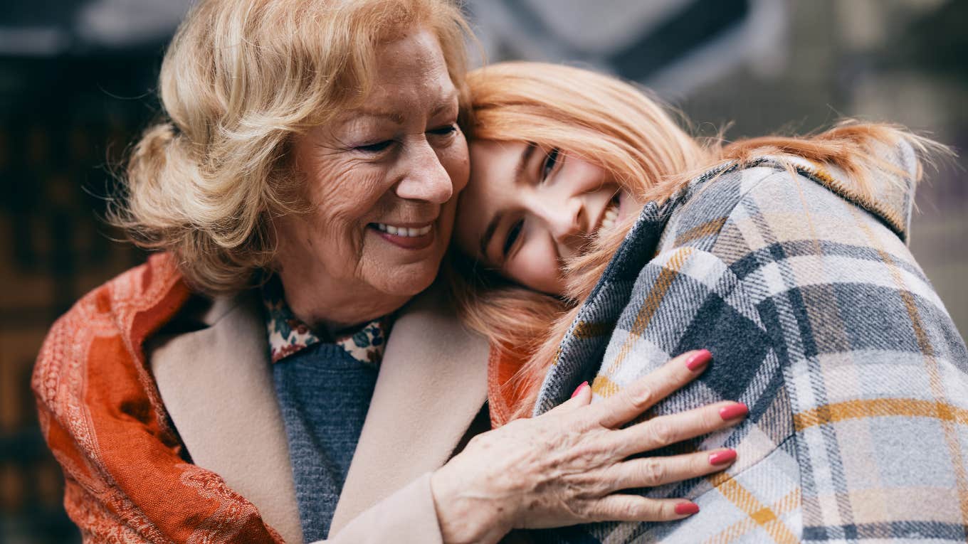 Grandmother and granddaughter hugging on the street in cold weather.