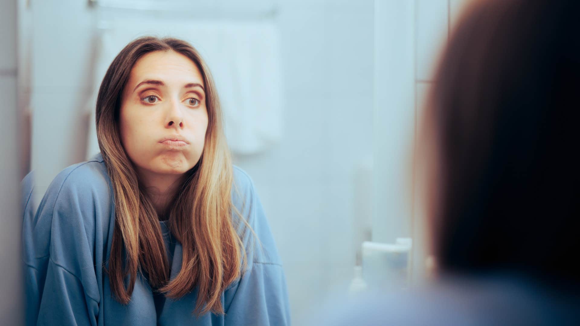 Unhappy woman looking in the mirror feeling overwhelmed