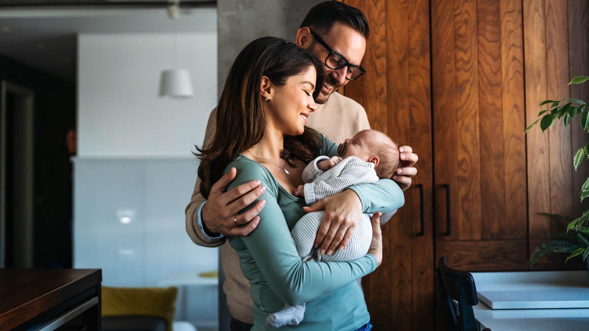 Happy young mother, father with new born baby at home