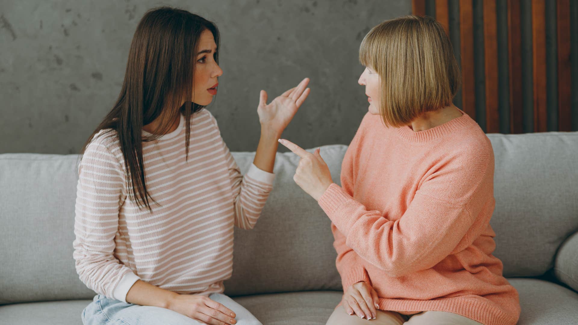 daughter and adult mom having heated conversation on couch