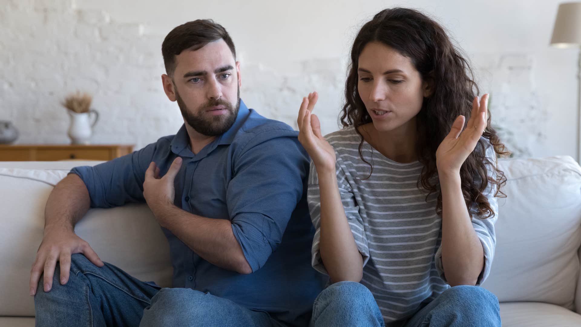 Couple arguing together on the couch.