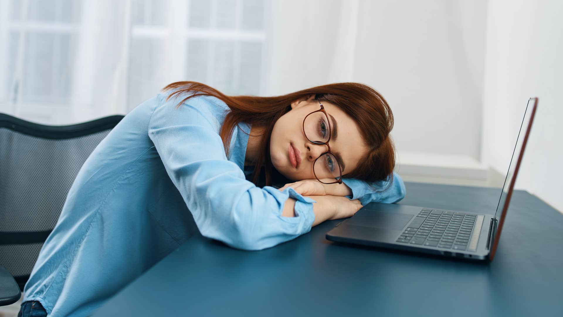 Tired woman leaned over her laptop. 