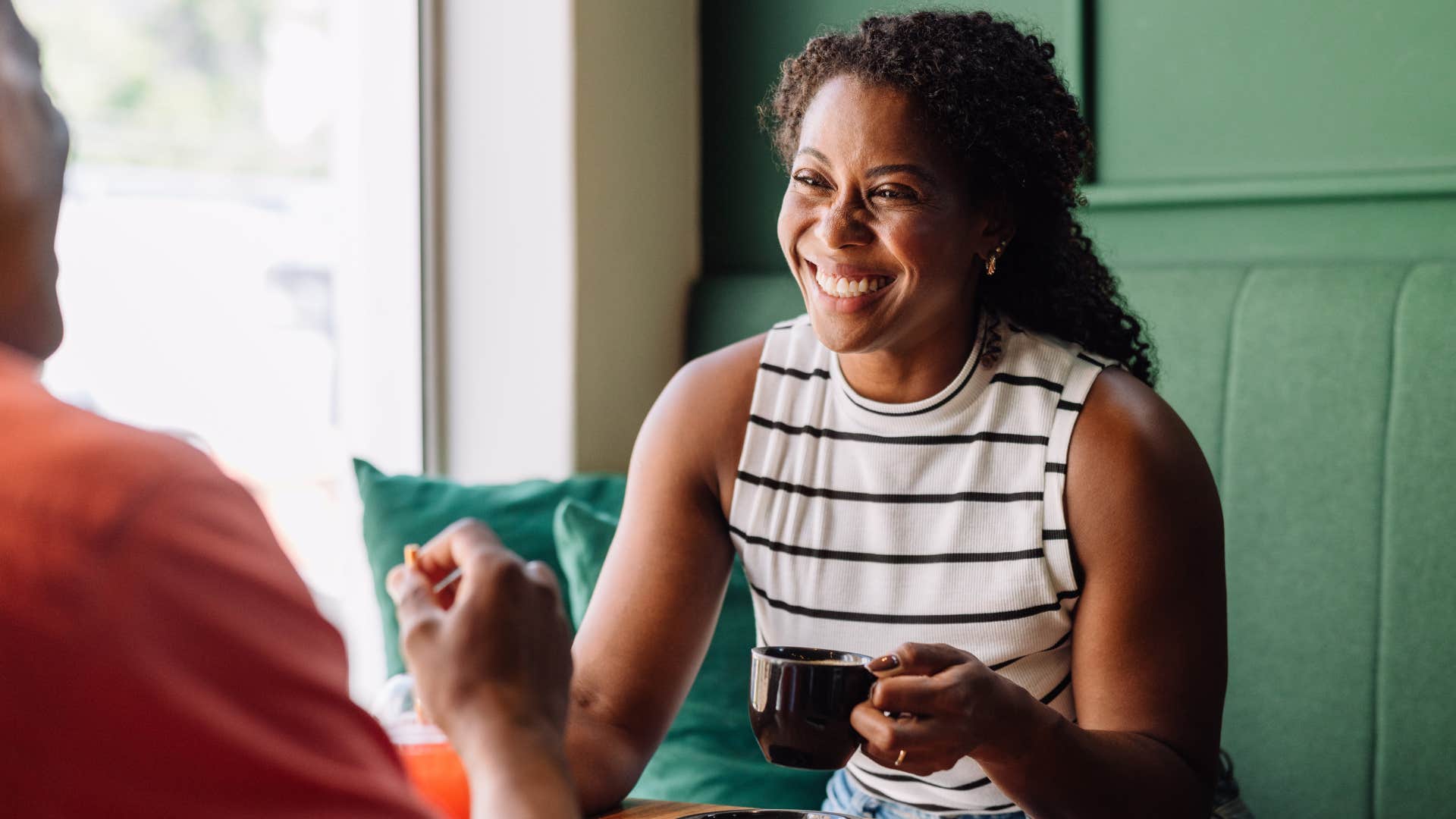 Woman smiling and talking to a man across the table. 