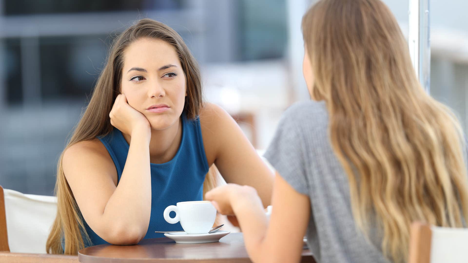 Woman looking annoyed while her friend speaks to her.