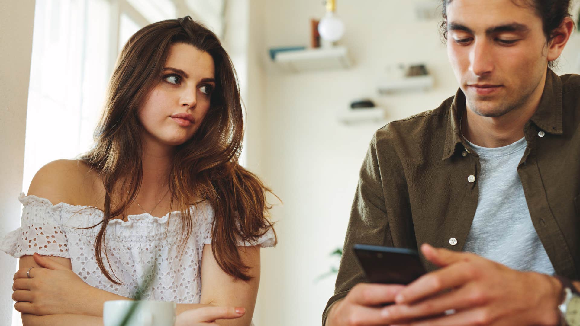 Woman staring at her boyfriend on his phone.