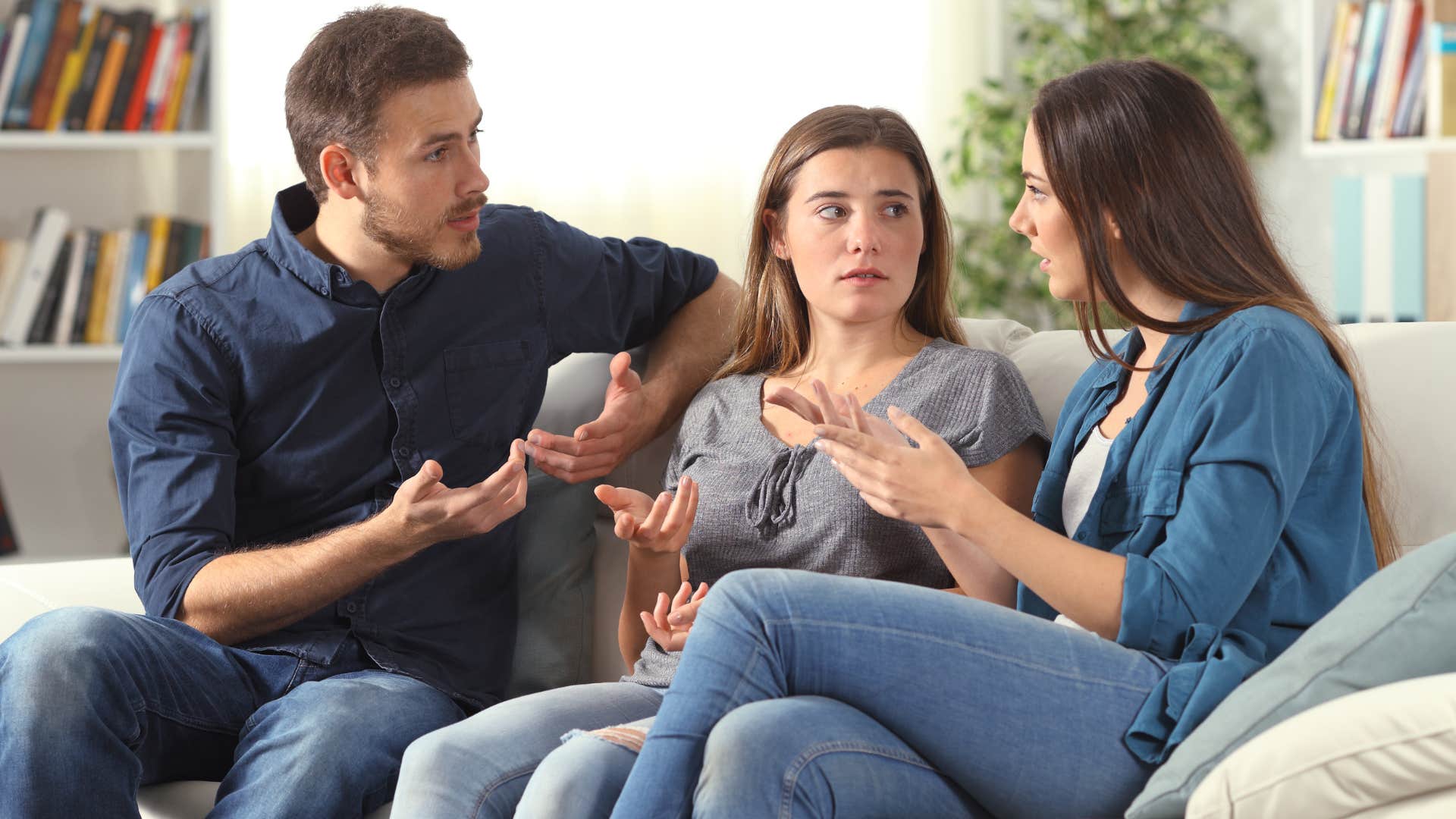 Three people having an argument sitting closely on a couch.