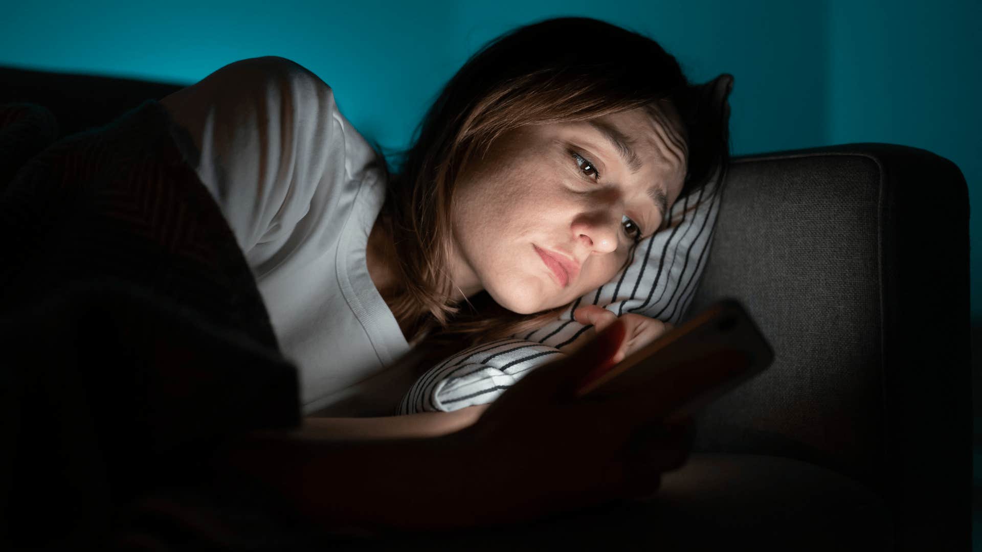 sad woman looking at her phone in the dark