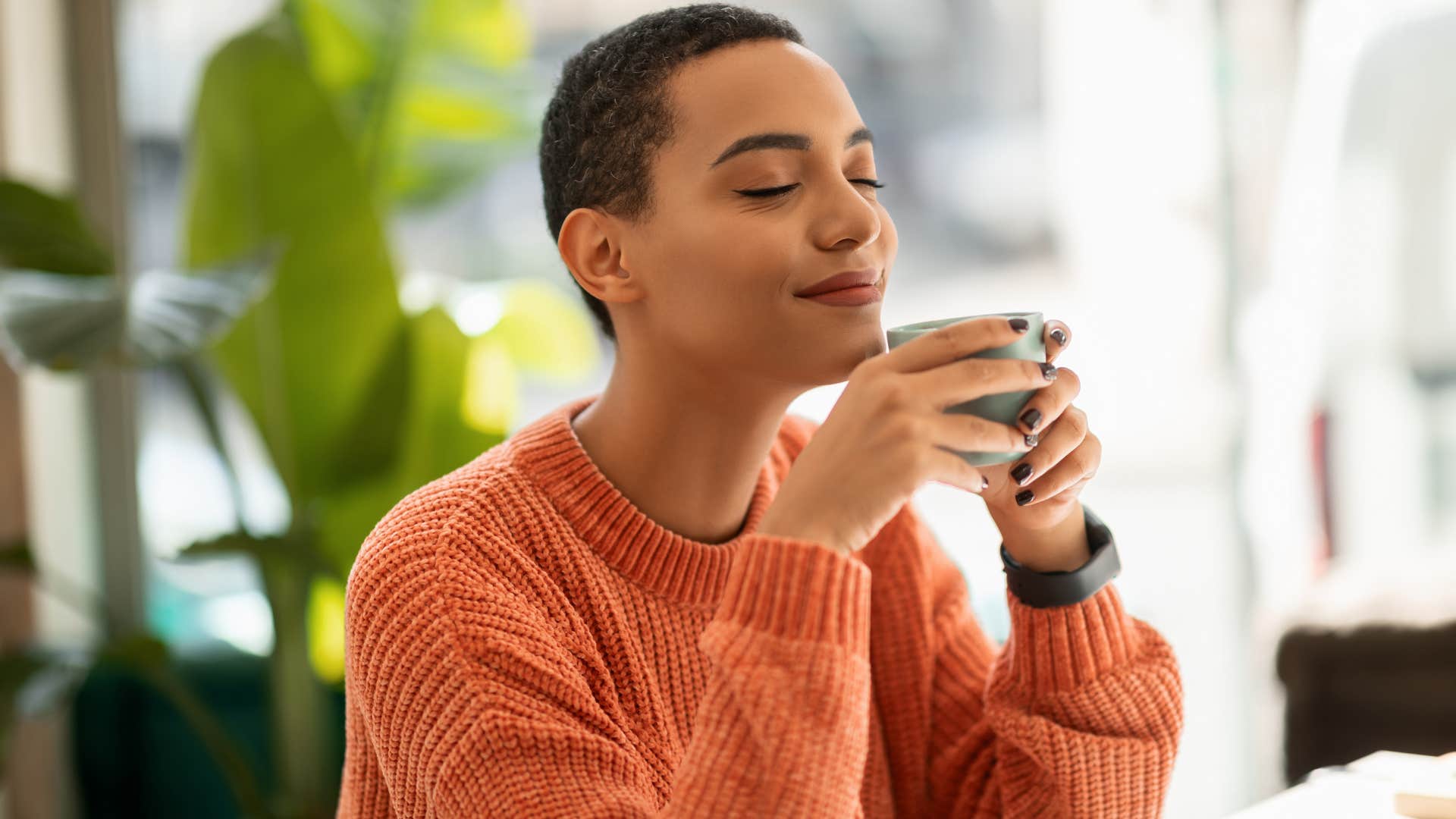 Woman smiling and drinking tea at home.