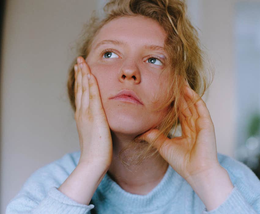 stressed out woman with blonde hair rubs her face