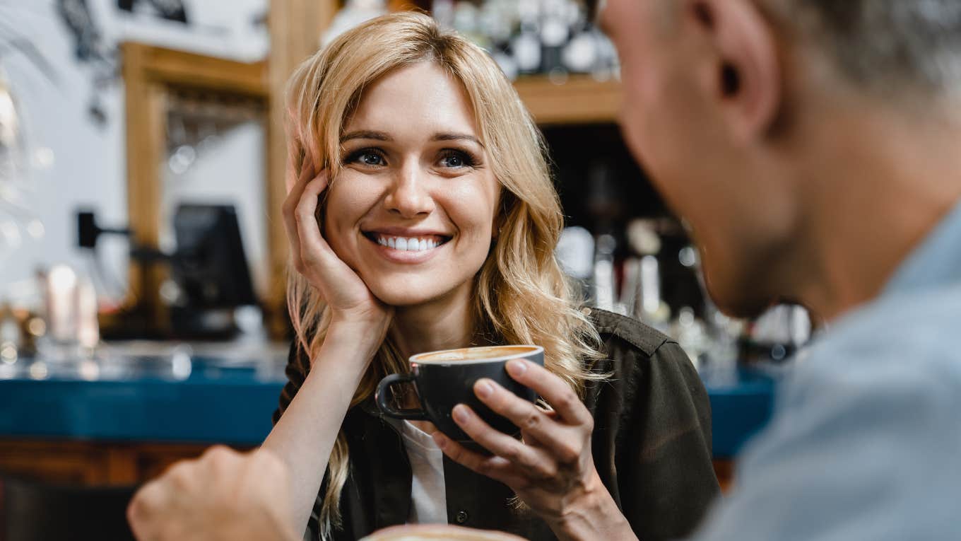 woman smiling holding coffee in a conversation