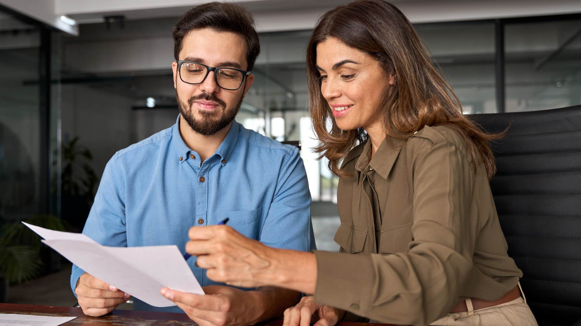 Co-workers talking and looking at a paper together.