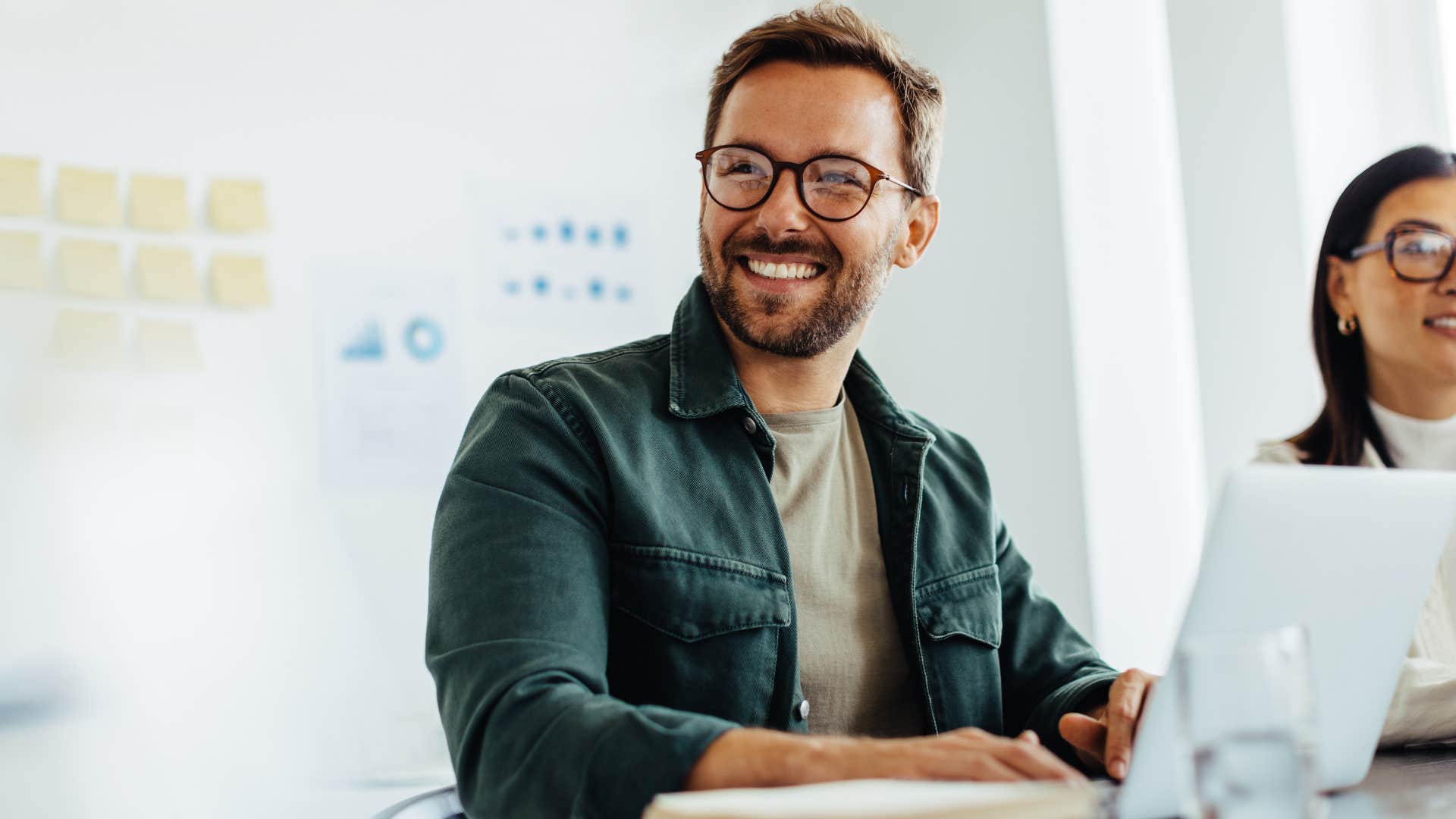 Man smiling while sitting in a work meeting.