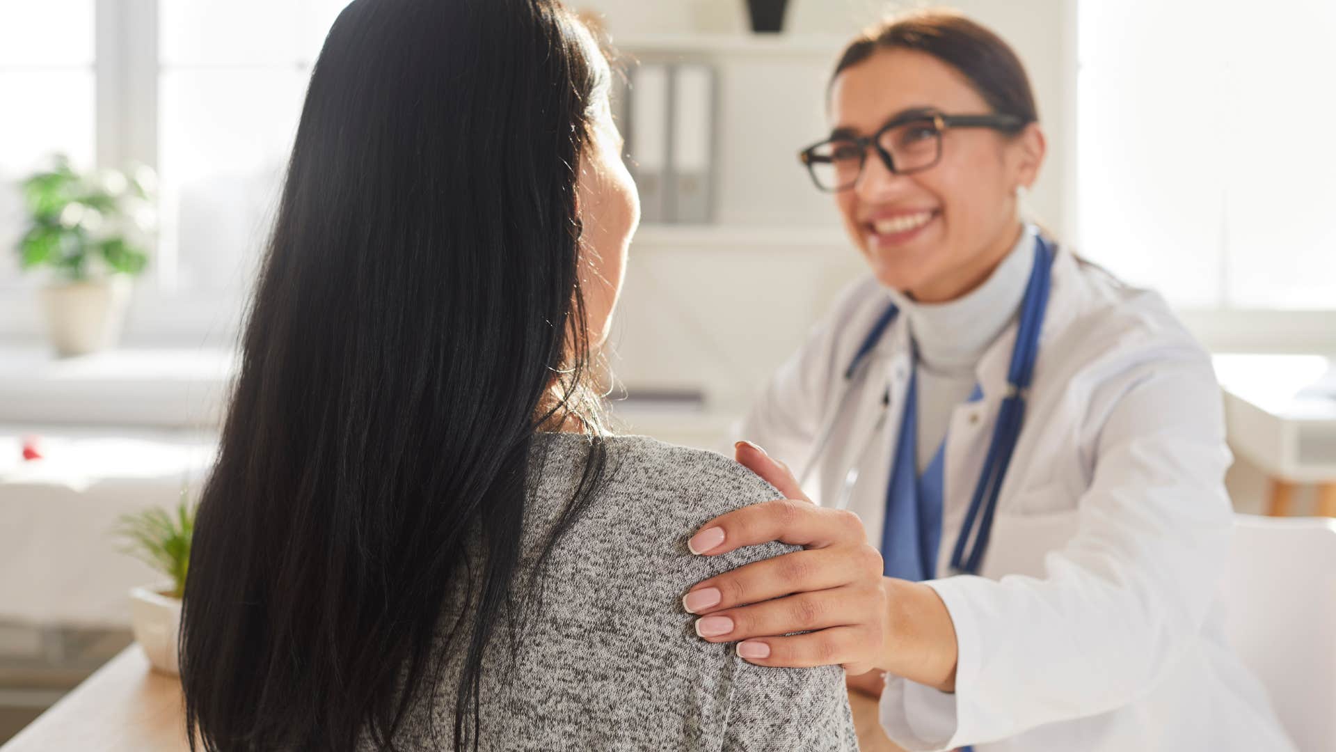 Female doctor smiling and touching a woman on her shoulder.