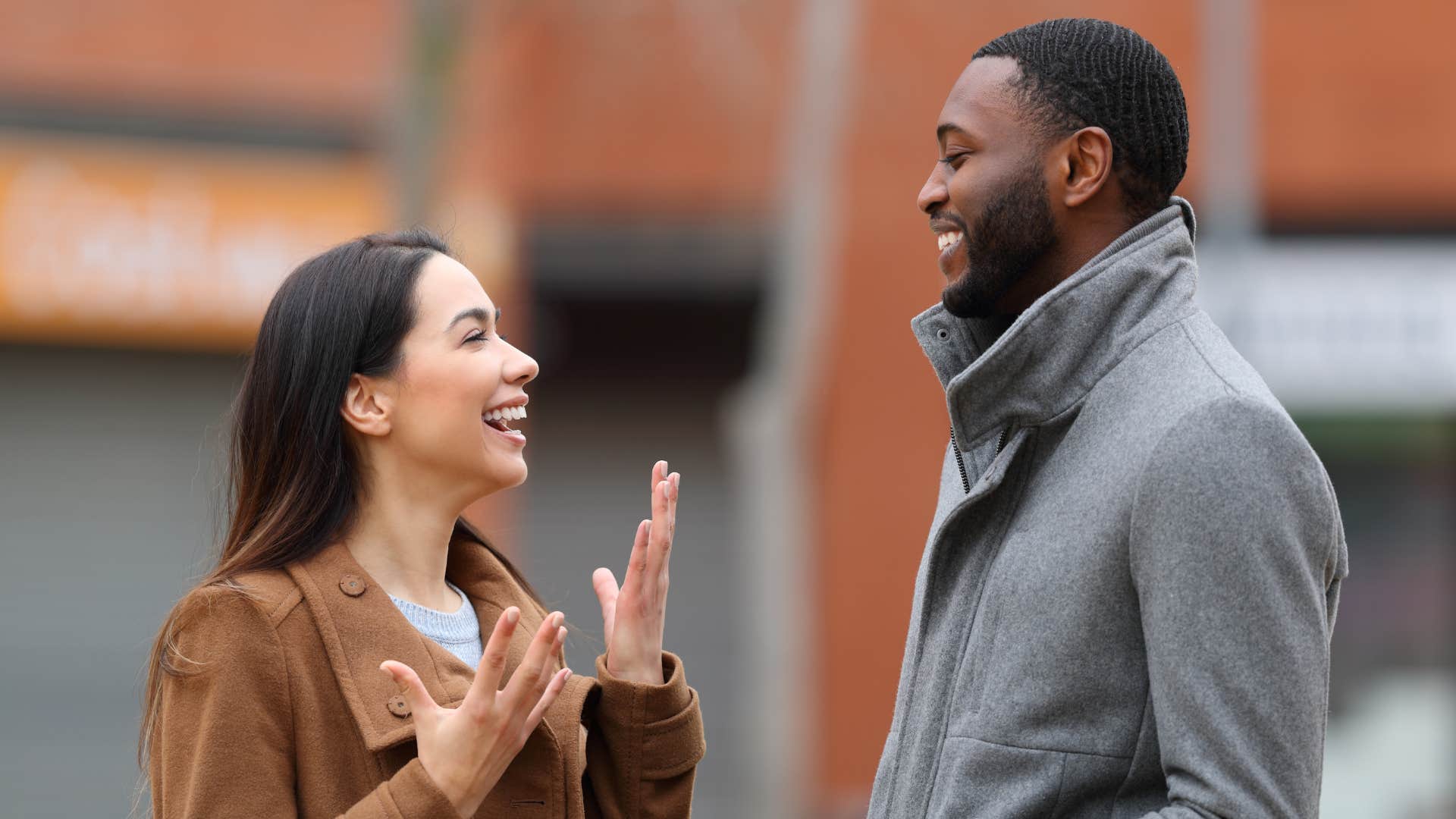 Couple smiling and talking to each other outside.