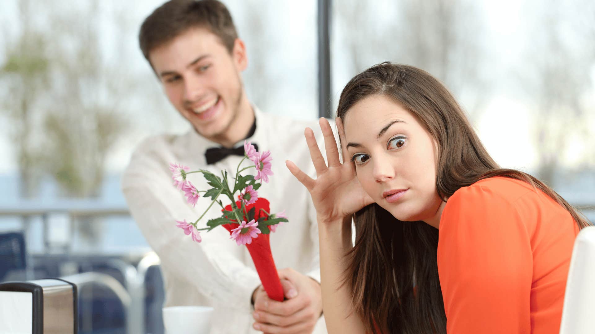 woman ignoring man trying to give her flowers