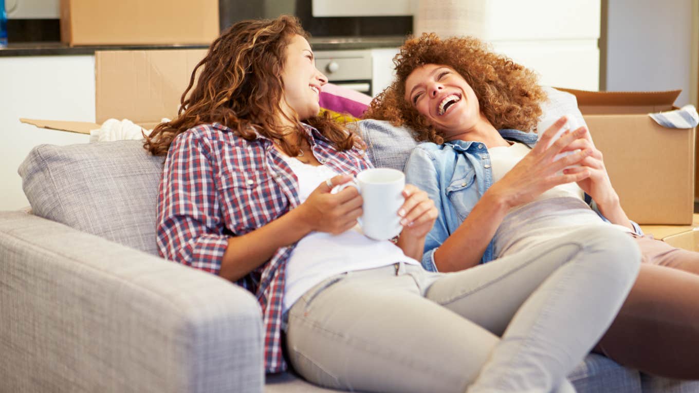 Two Women Relaxing On Sofa With Hot Drink In New Home