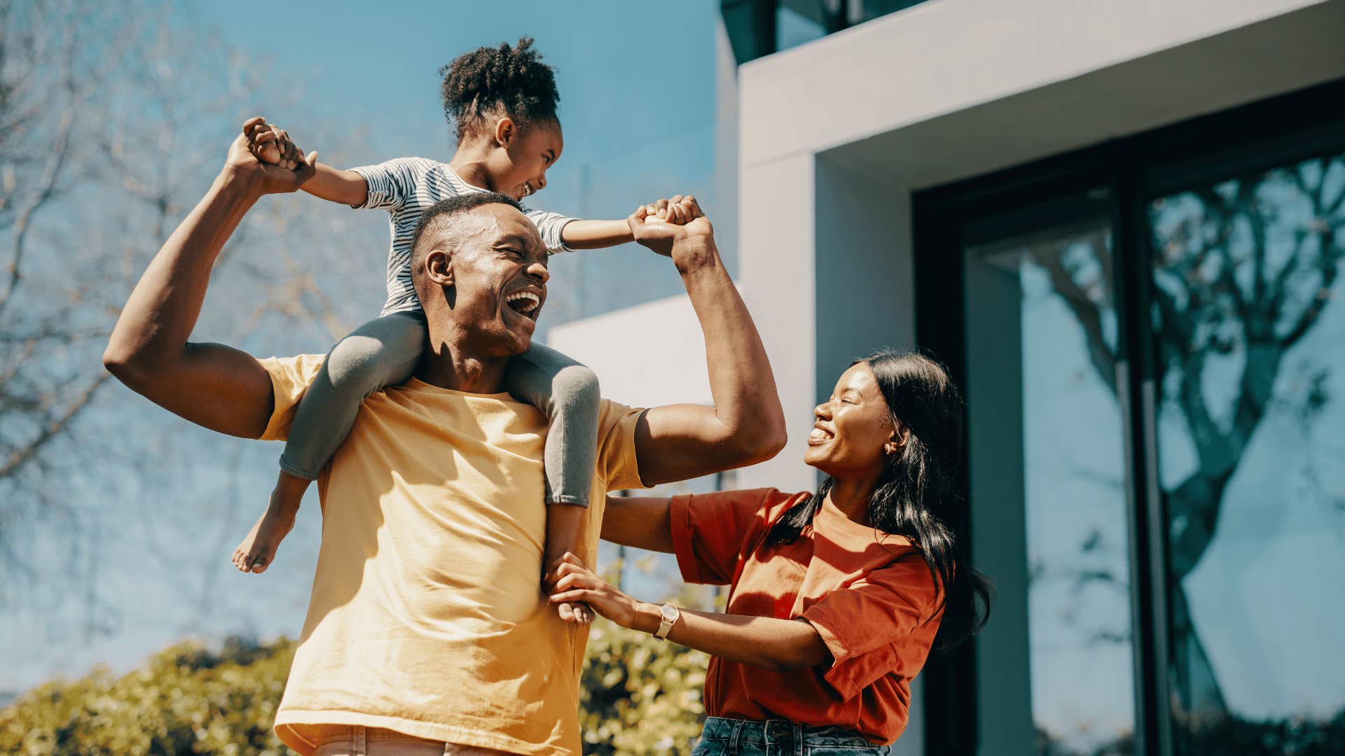 Child rides father's shoulders while mother supports them