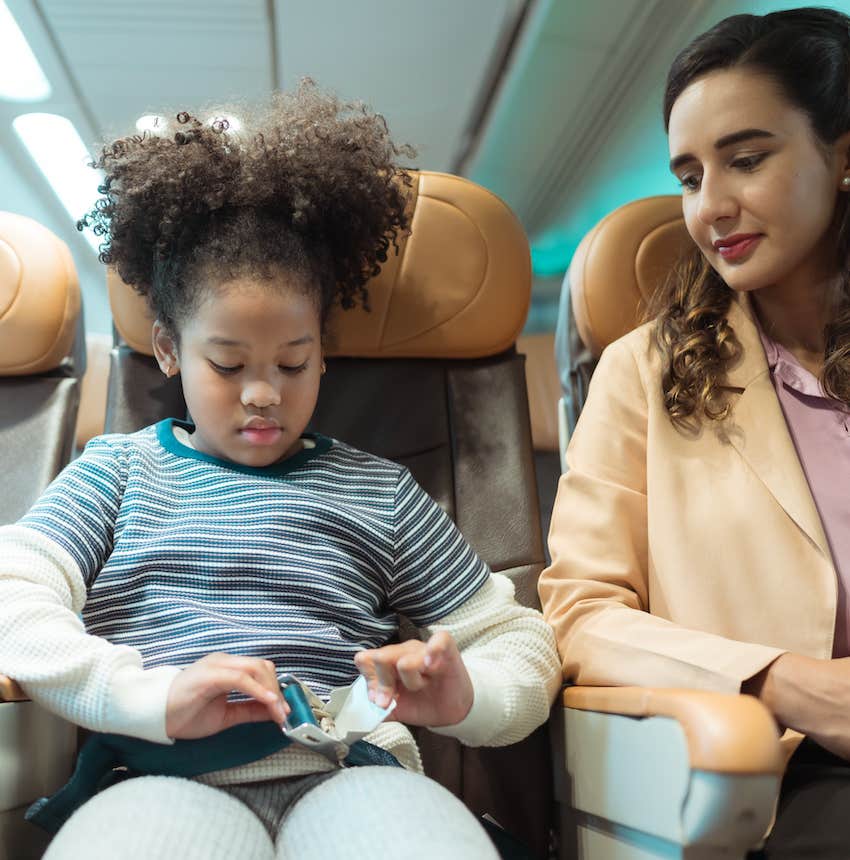 Girl in airplane seat buckles her seat belt and is aware