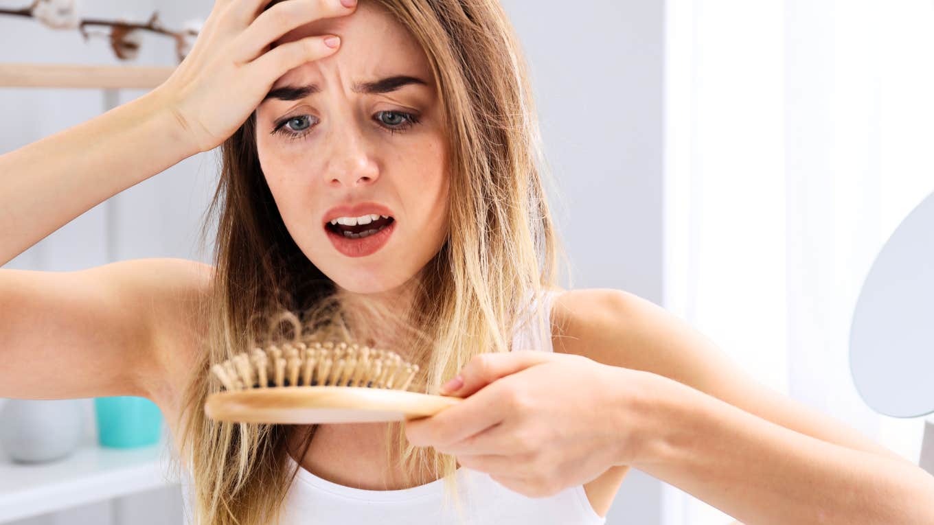 Woman looking at hair brush, hair falling out.