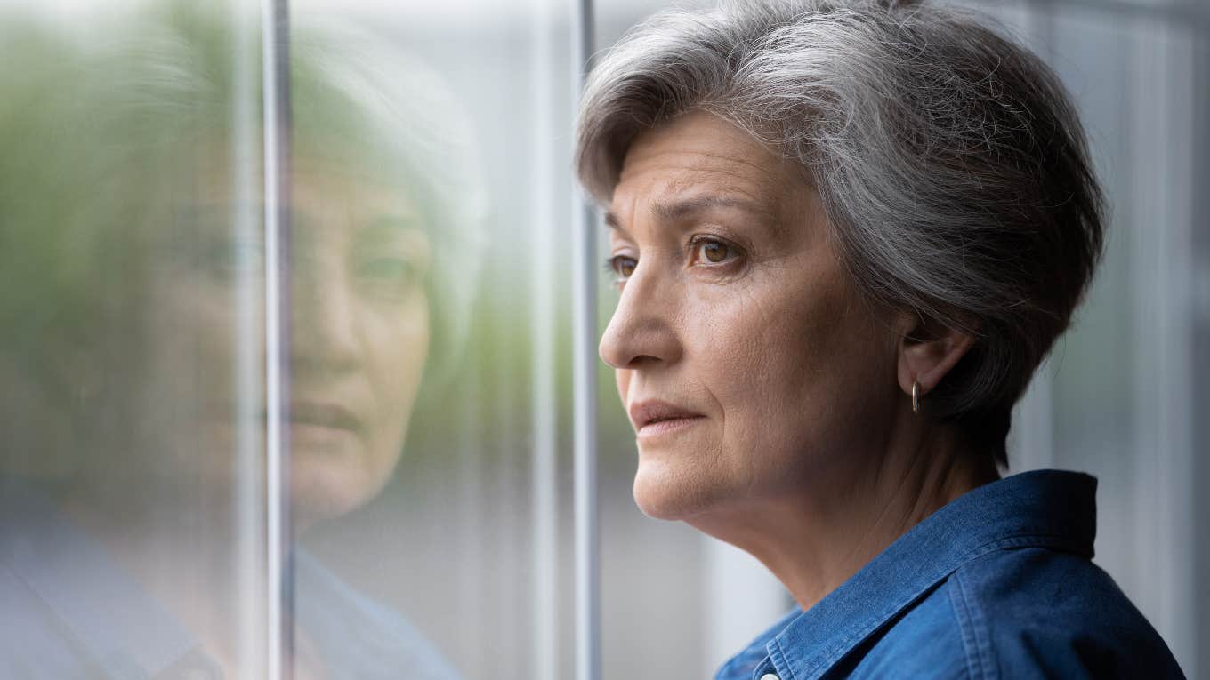 widowed grandmother looking out the window feeling sad