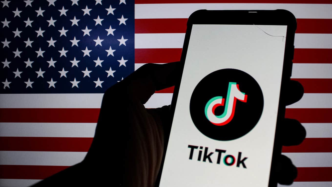 TikTok logo is displayed on a smartphone with Flag Of America in the background.