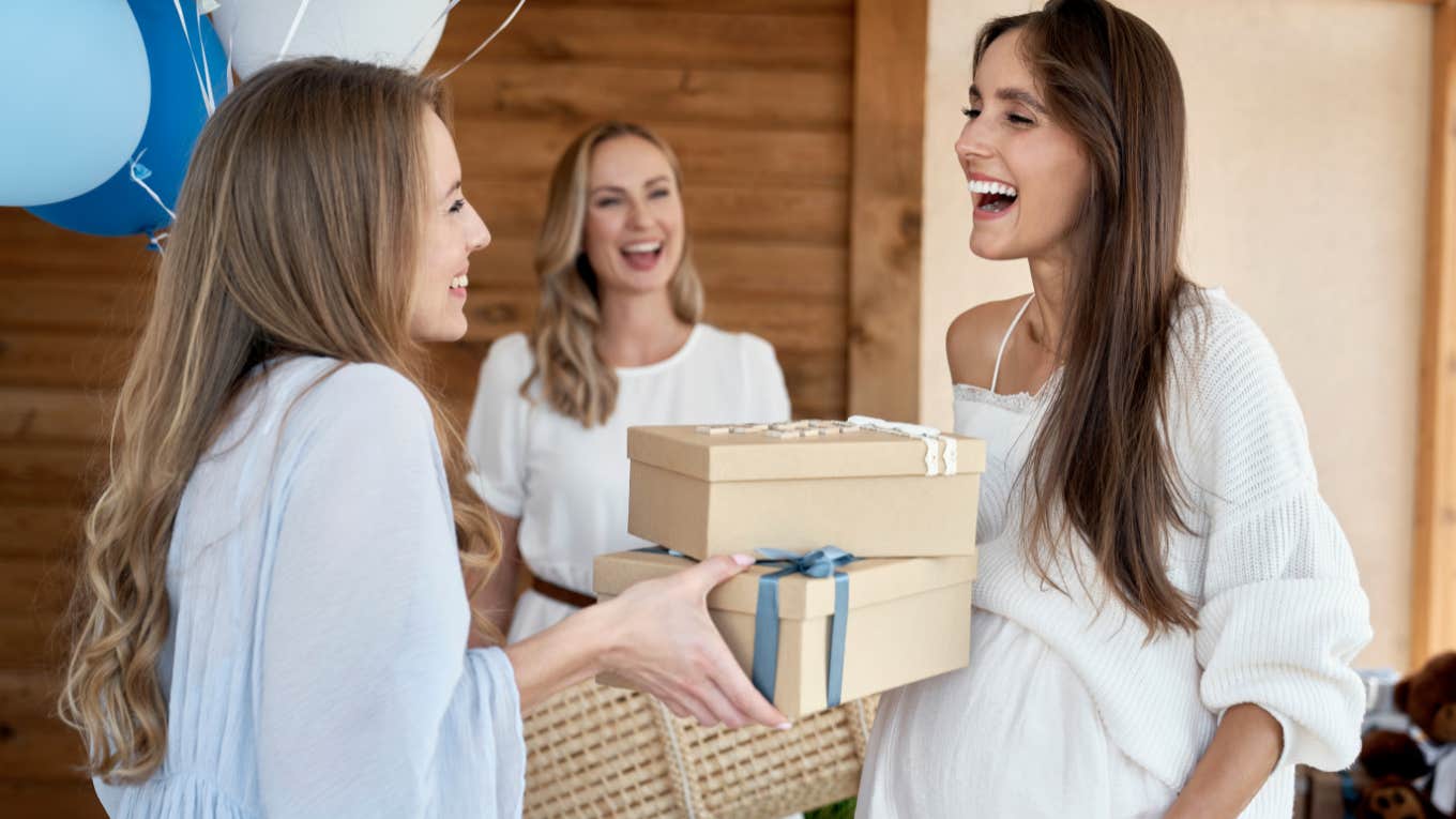 woman handing baby shower gifts to pregnant woman