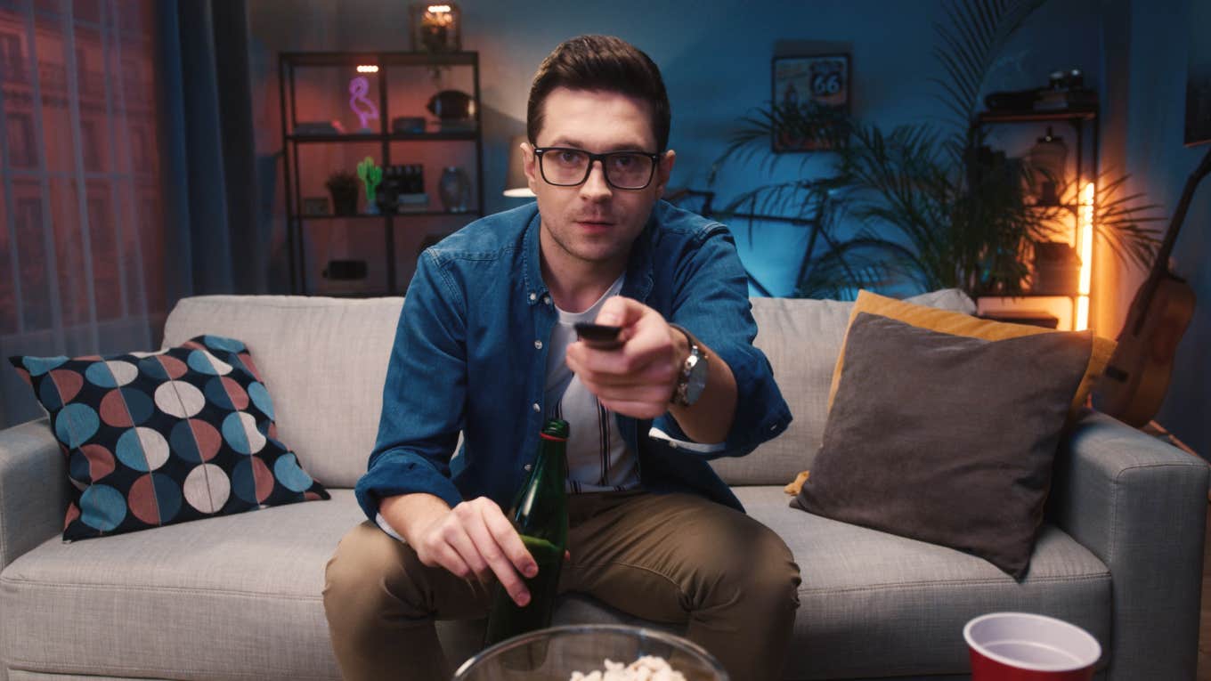 man sitting on couch holding remote watching TV