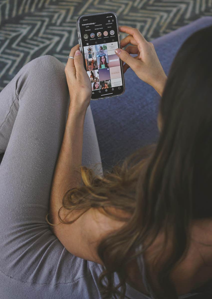 woman sitting on couch scrolling through Instagram on her phone