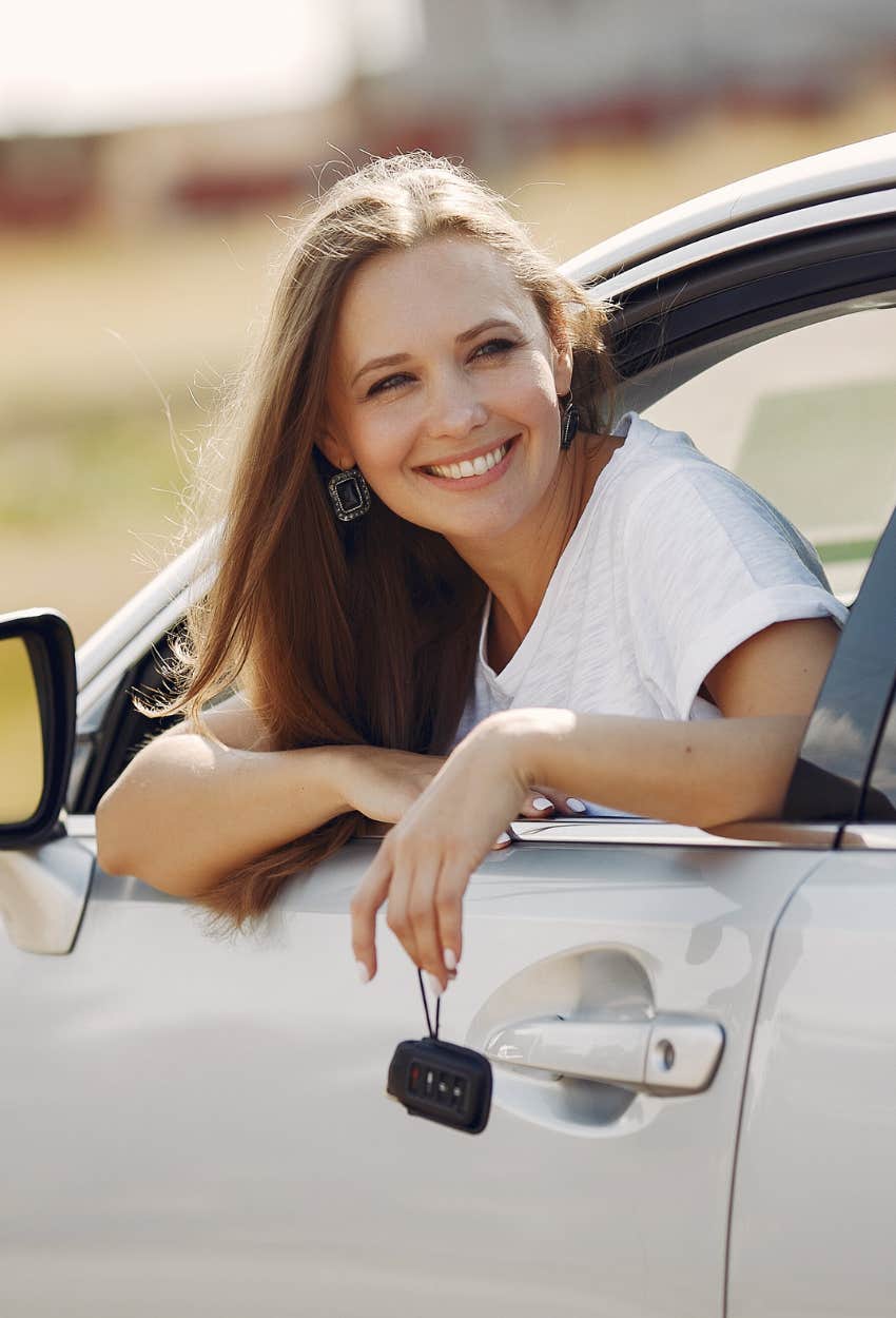 woman smiling with head out of the car window